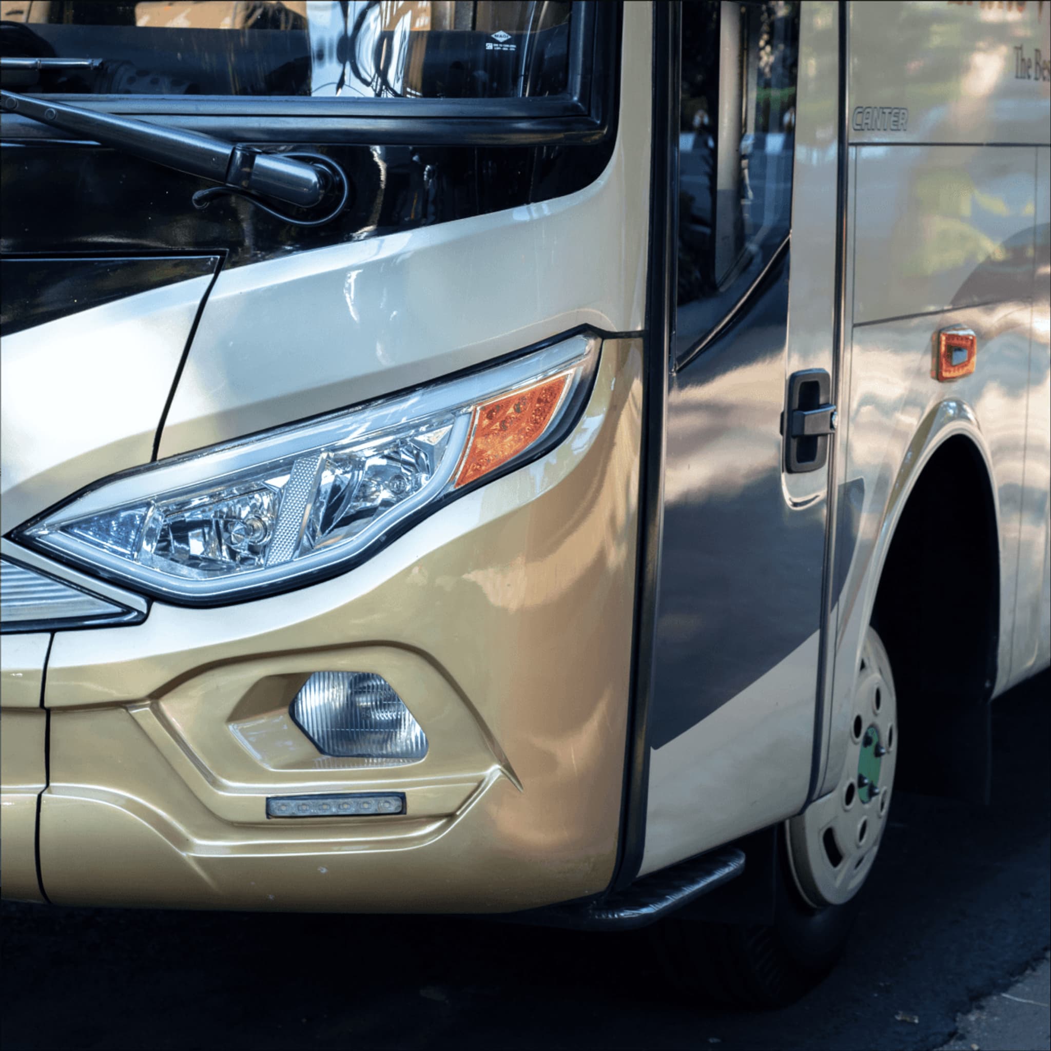 Front view of a modern, cream-colored bus showcasing its sleek design and headlights.